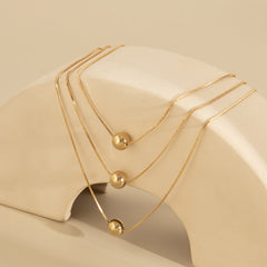 Stunning 18K gold-plated necklace set with three strands, adorned with a striking golden ball for a touch of elegance.