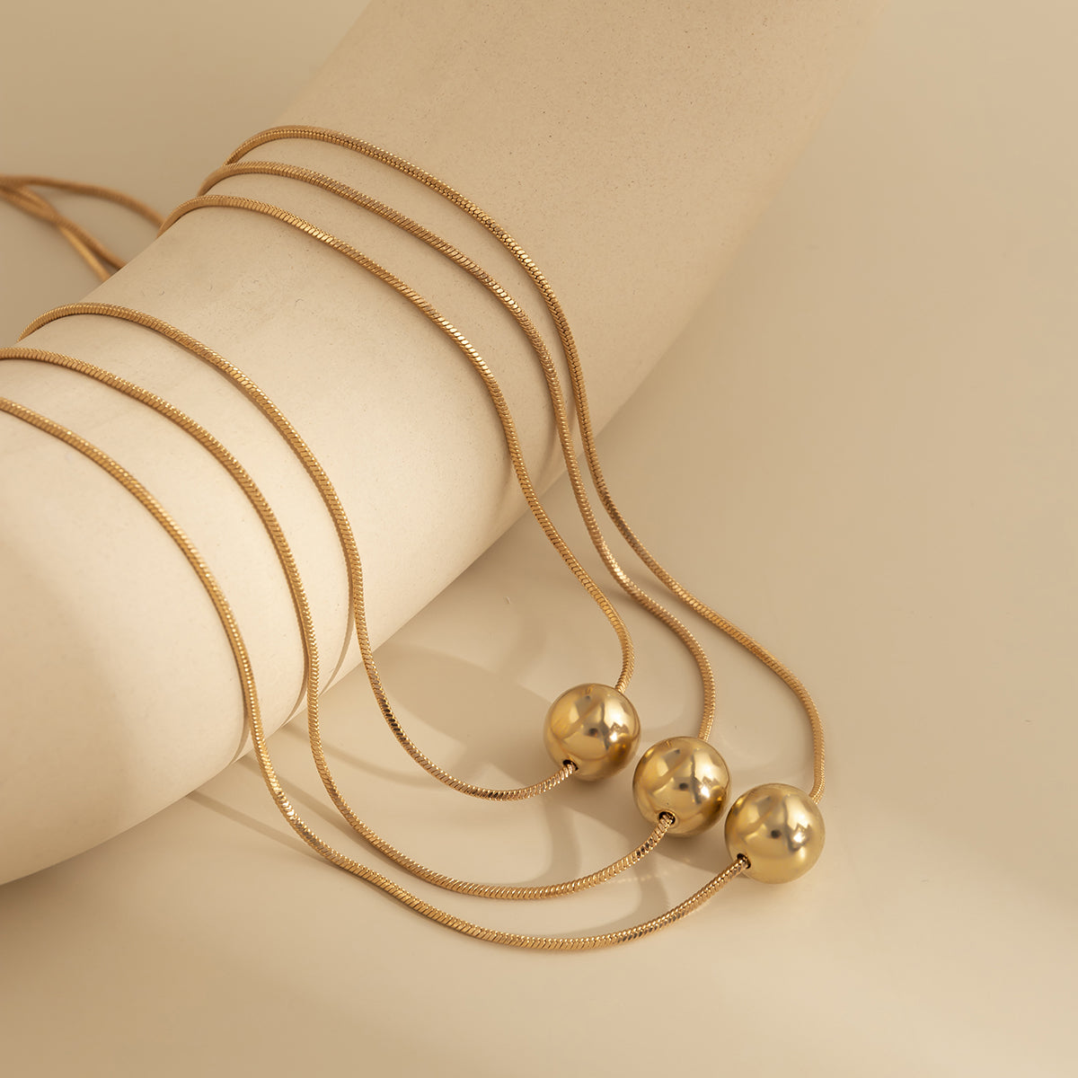 Beautiful 18K gold-plated necklace set featuring a golden ball design with three strands, perfect for any occasion.